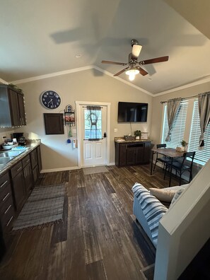 A kitchen with wooden cabinets, a clock, and a ceiling fan.