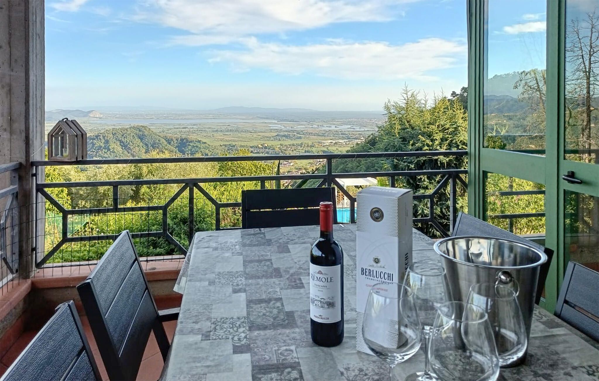 Een balkon met een tafel, een fles wijn en een wijnkoeler.