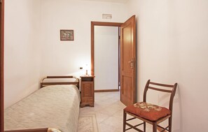 Ein Schlafzimmer mit einem Bett, einem Nachttisch, einem Sessel und einer Tür.