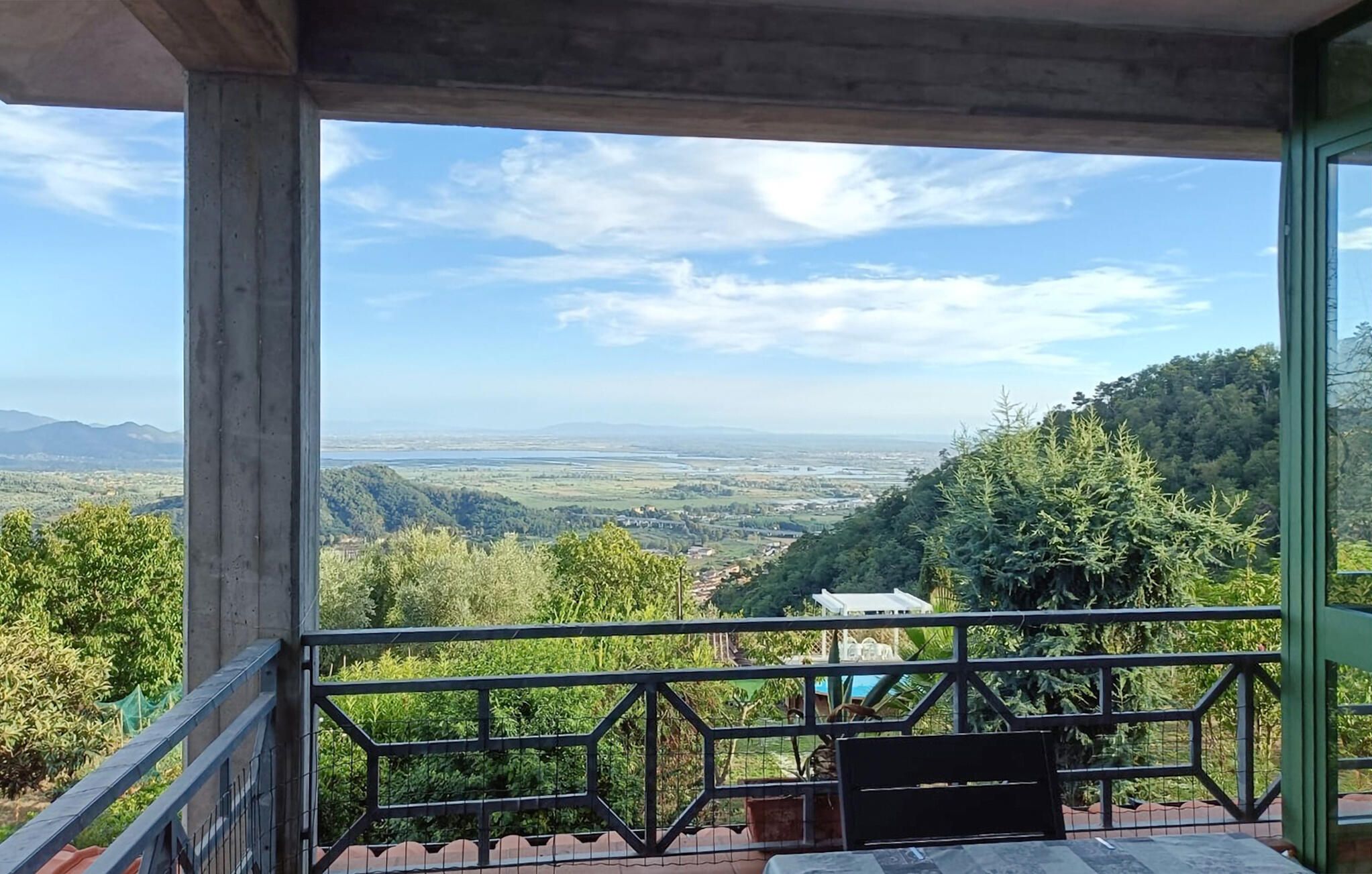 A balcony with a view of a valley and distant mountains.