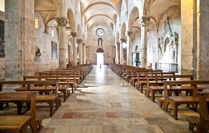 A church interior with rows of wooden pews, stone flooring, and a central aisle leading to an altar. - 3 bedroom awesome apartment in Prata (Prata)