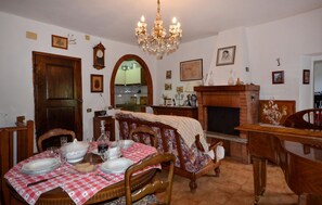 A dining room with a table set for four, a fireplace, and a chandelier. - 3 bedroom awesome apartment in Prata (Prata)