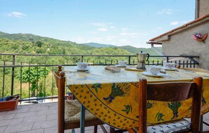 Mesa posta com xícaras de chá e um bule em varanda com vista para uma paisagem verde.