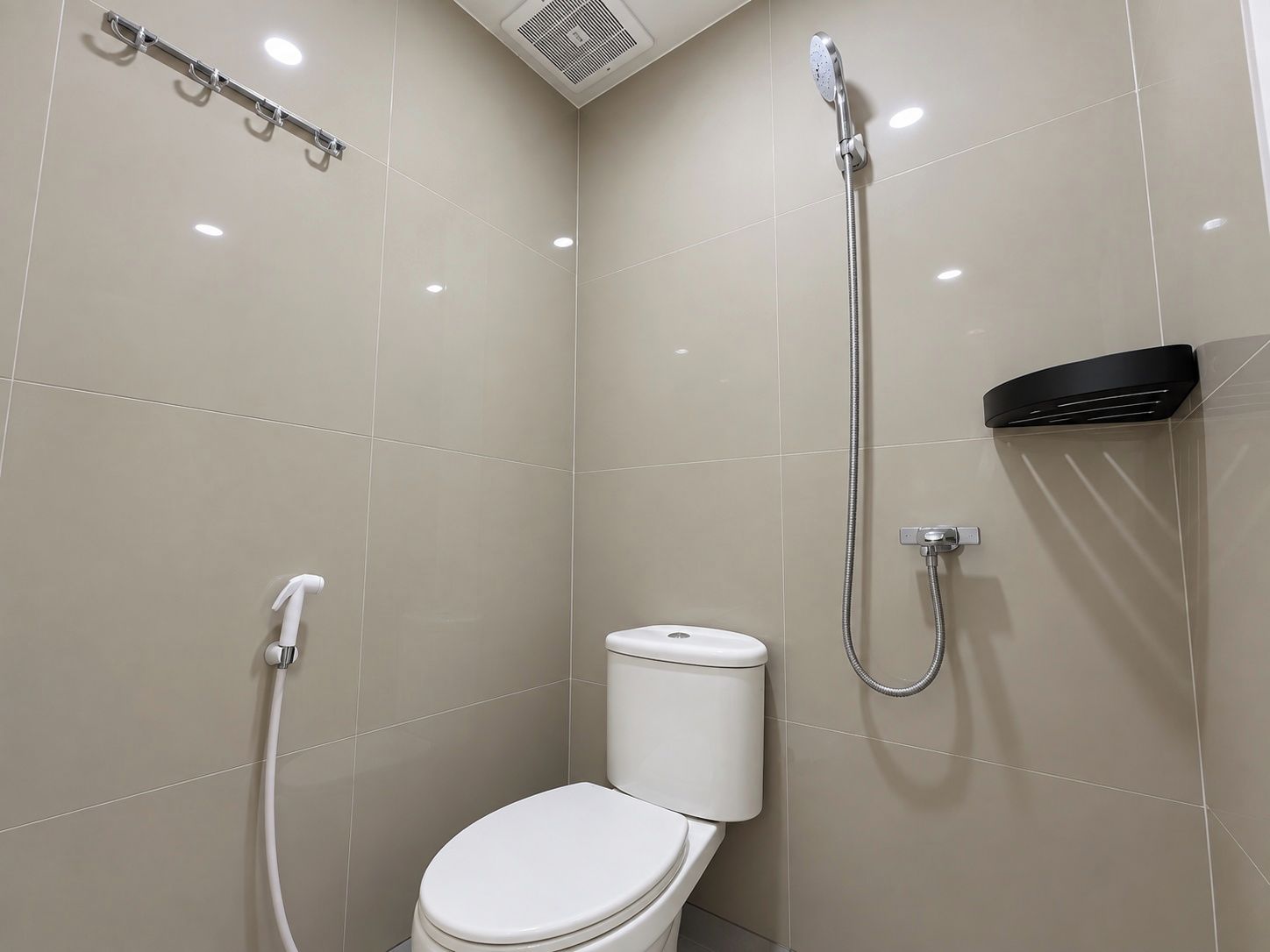 Een moderne badkamer met toilet, douche met handdouche en een wandradiator.