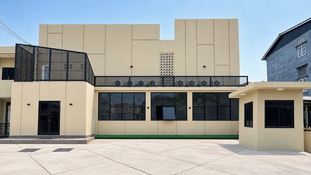 A modern building with a flat roof, large windows, and a central air conditioning unit.