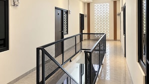A modern hallway with a glass railing, doors, and a patterned wall.