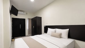 A hotel room with a bed, a flat-screen TV mounted on the wall, a wardrobe, and a door.