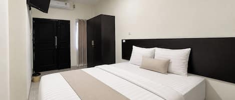 Habitación de hotel con cama, televisor de pantalla plana en la pared, armario y puerta.