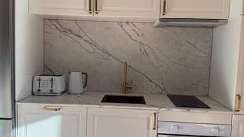 A kitchen with white cabinetry, a marble backsplash, a built-in oven, and a toaster.