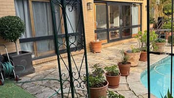 A courtyard with a swimming pool, potted plants, and a metal gate.