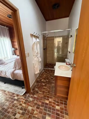 Een badkamer met een douche, wastafel en spiegel.