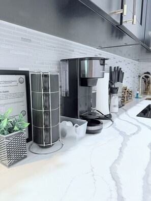 Eine moderne Küche mit einer Kaffeemaschine, einem Glasbehälter und einem Blumentopf.