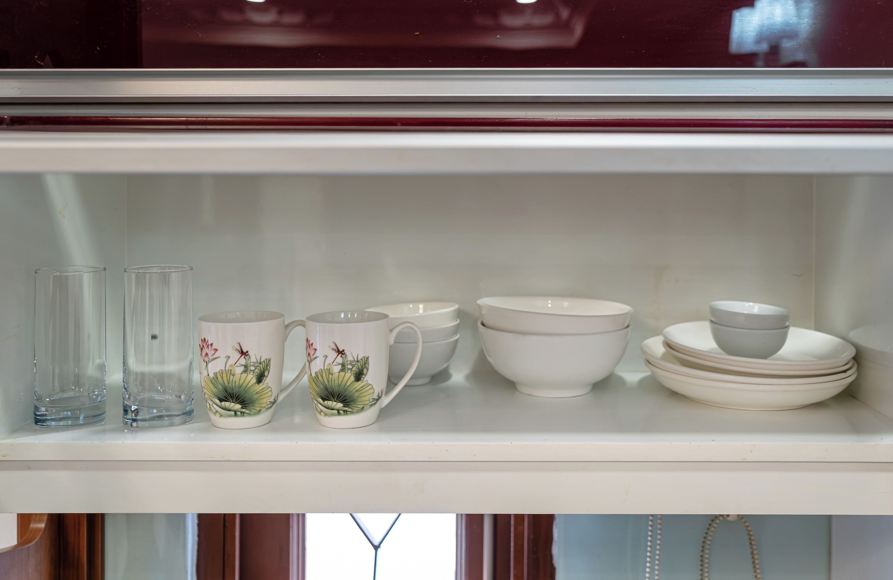 A shelf with various glassware and ceramic items, including cups, bowls, and plates.