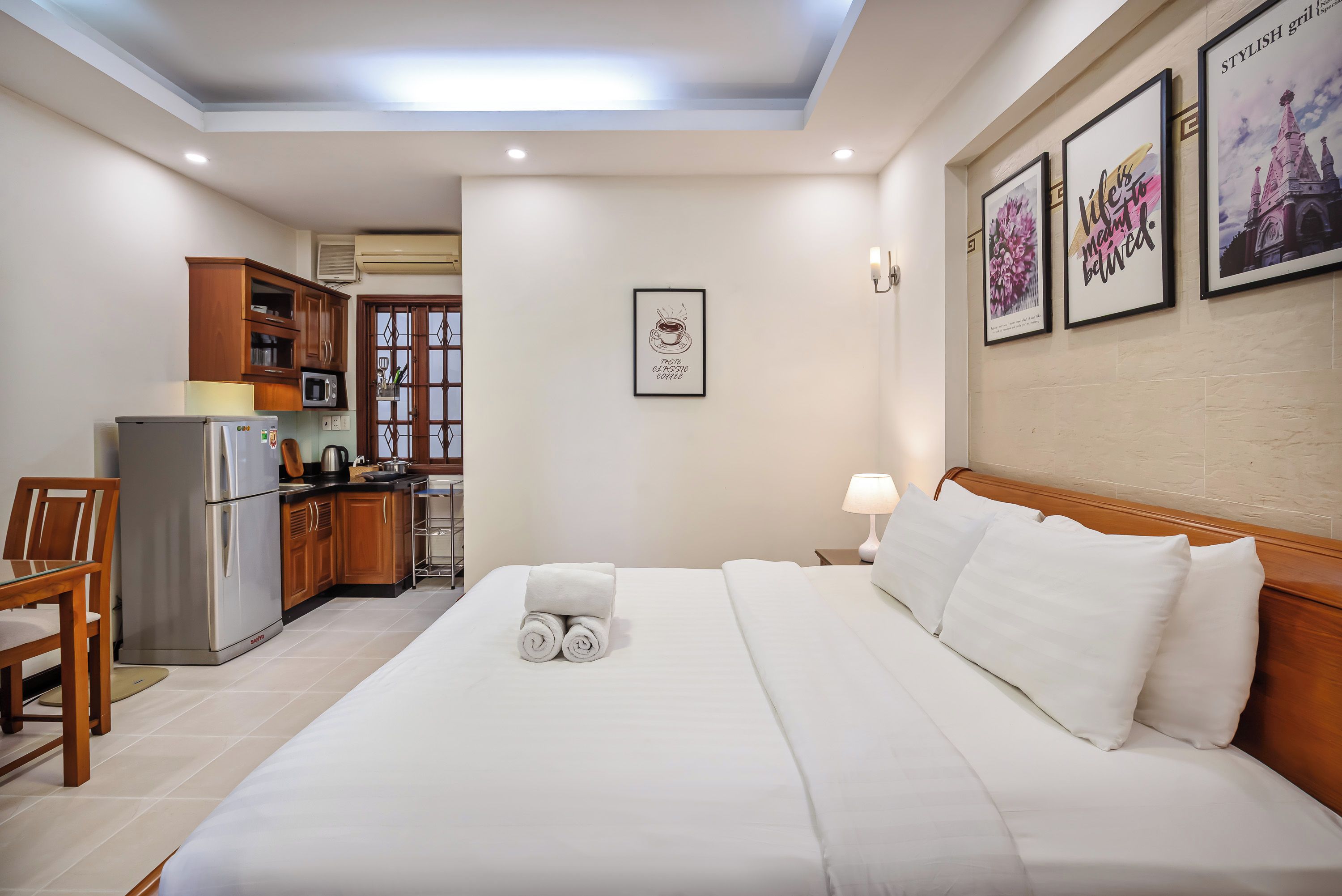 A hotel room with a bed, a desk, a microwave, and a kitchenette.