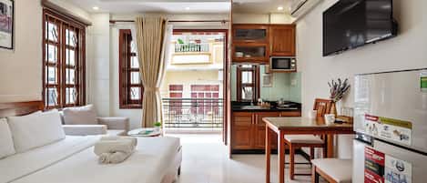 A hotel room with a bed, a desk, a TV, and a kitchen area.