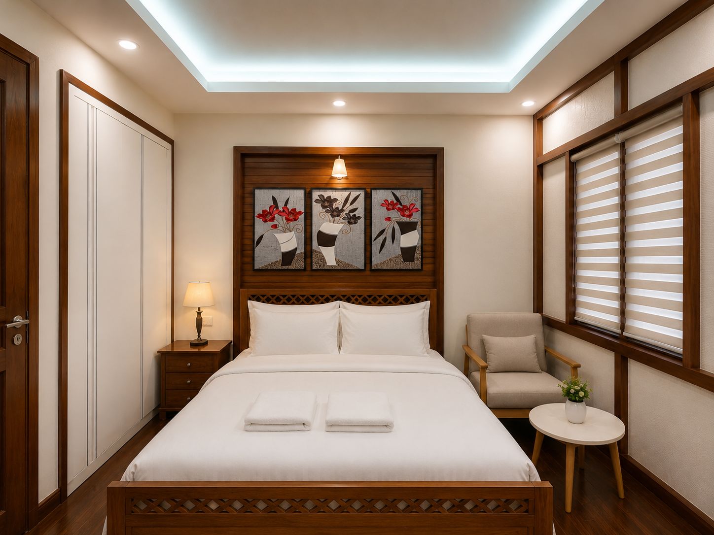 A hotel room with a bed, a nightstand, a chair, a small table with a plant, and artwork on the wall.
