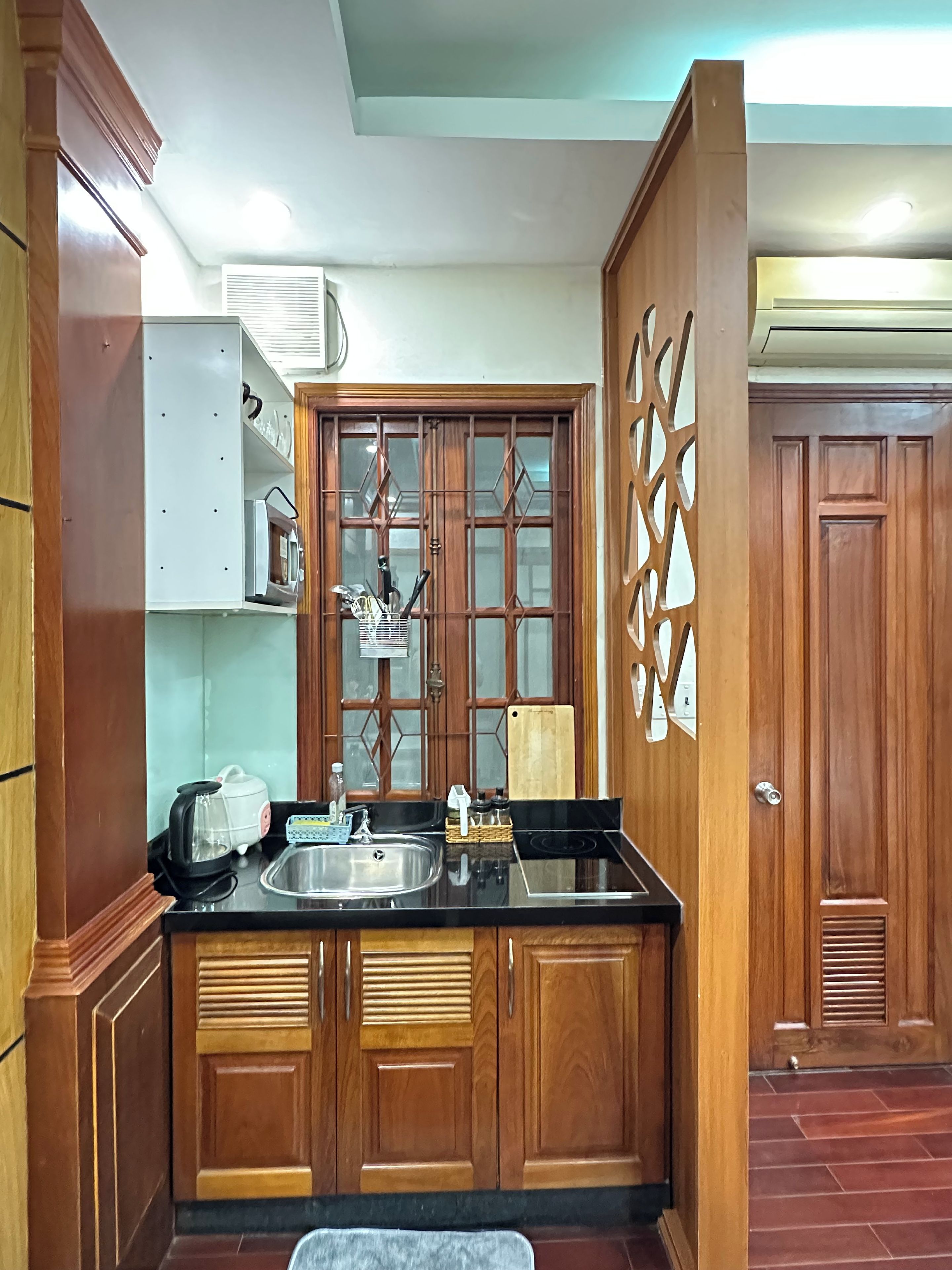 Una cocina con armarios de madera, encimera negra, microondas, tostadora y pileta.