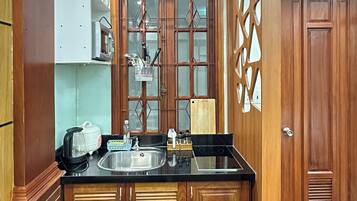 Una cocina con armarios de madera, encimera negra, microondas, tostadora y pileta.