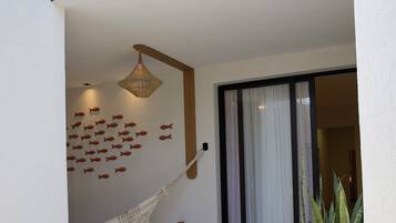 Un espace intérieur moderne avec un hamac, un mur décoratif, une grande plante en pot et une porte-fenêtre coulissante.