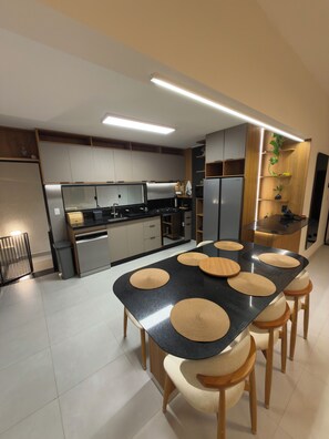 A modern kitchen with a central island, built-in appliances, and a dining area with stools.