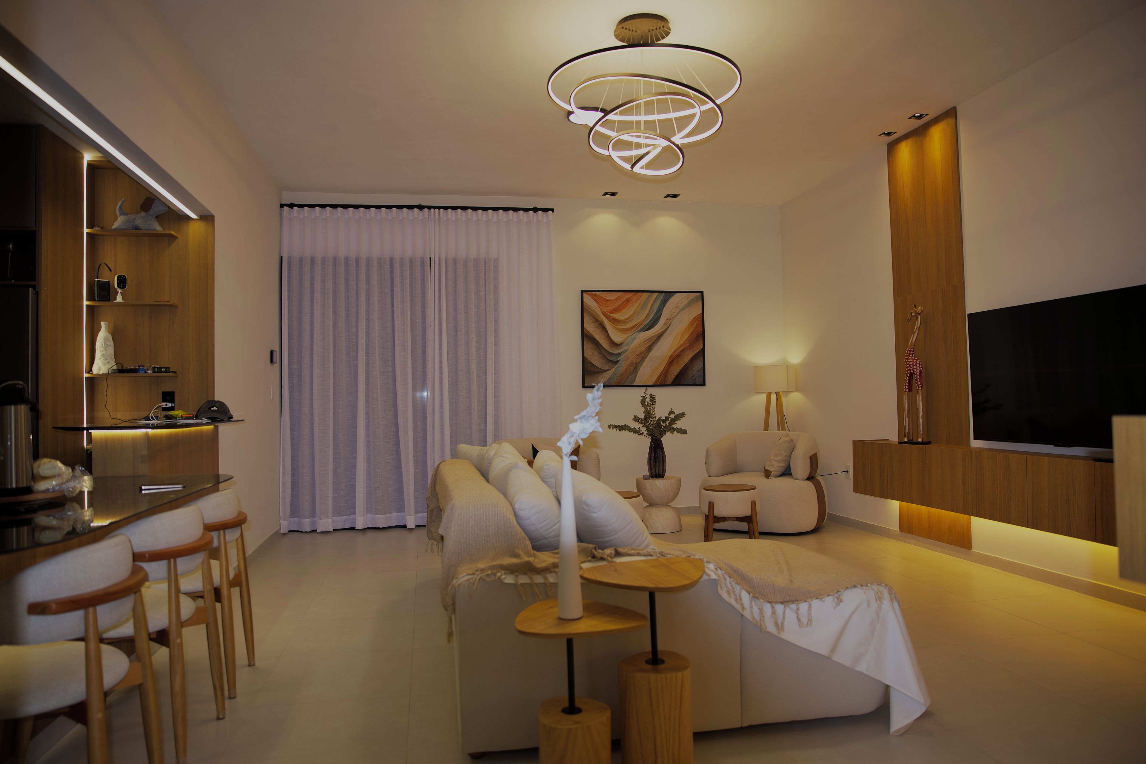 Uma sala de estar moderna com sofá, mesa de centro, televisão e área de jantar com cadeiras e mesa.