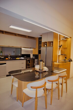 A modern kitchen with a central island, wooden chairs, and built-in appliances. - Casa Cazzoto, just steps from the Atalaia beachfront, the crab walkway, and the arches. (Aracaju)