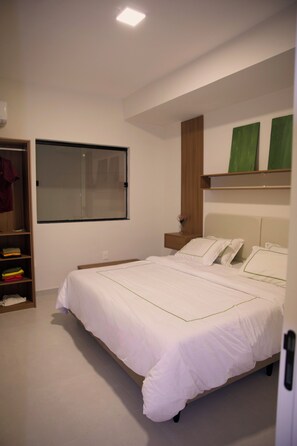 A bedroom with a large bed, a wardrobe, a mirror, and a window.