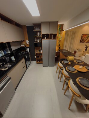 A modern kitchen with a central island, built-in appliances, and a dining area with chairs and a table set for four.