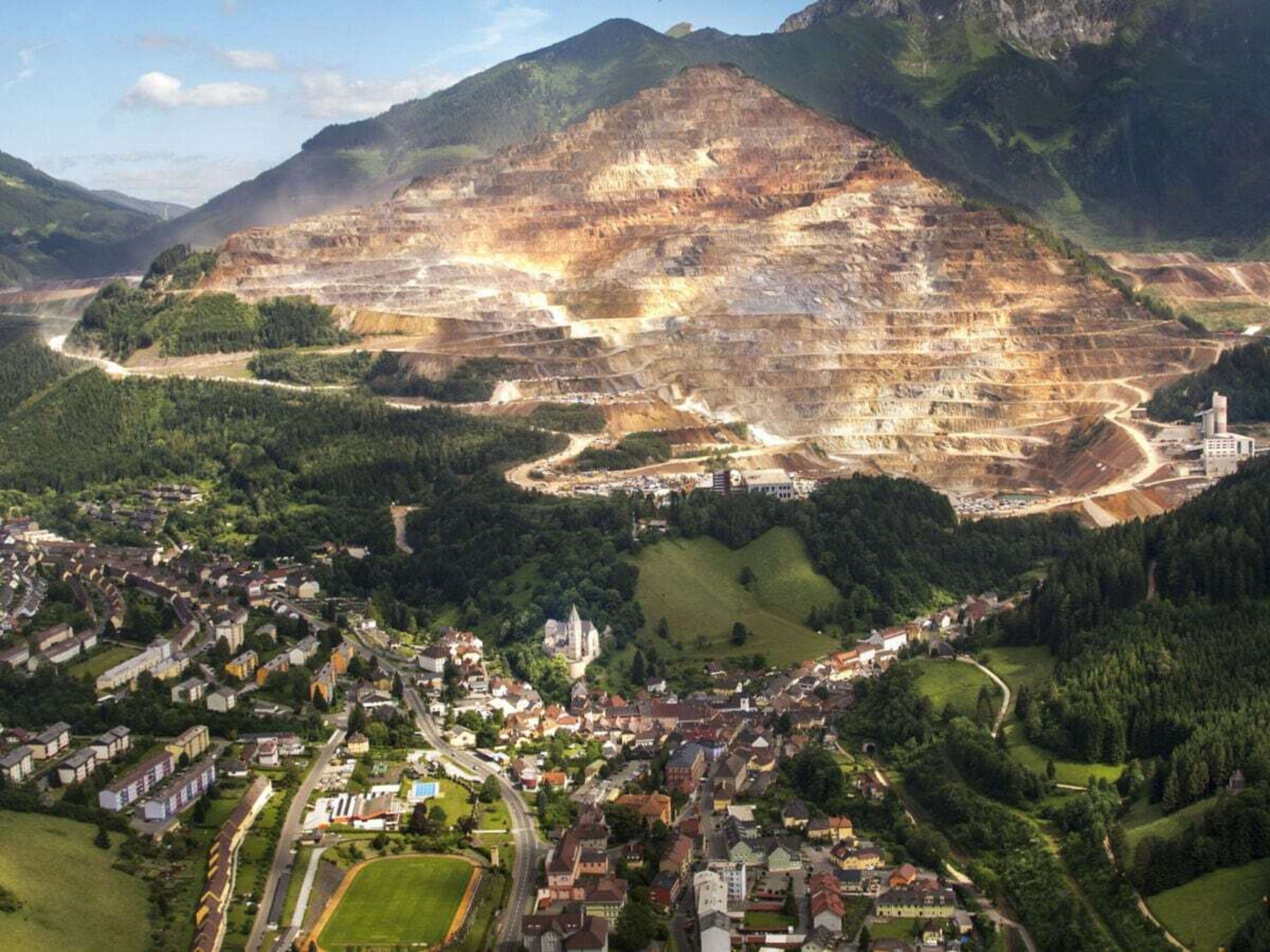 A town nestled in a valley with a large open-pit mine in the background.