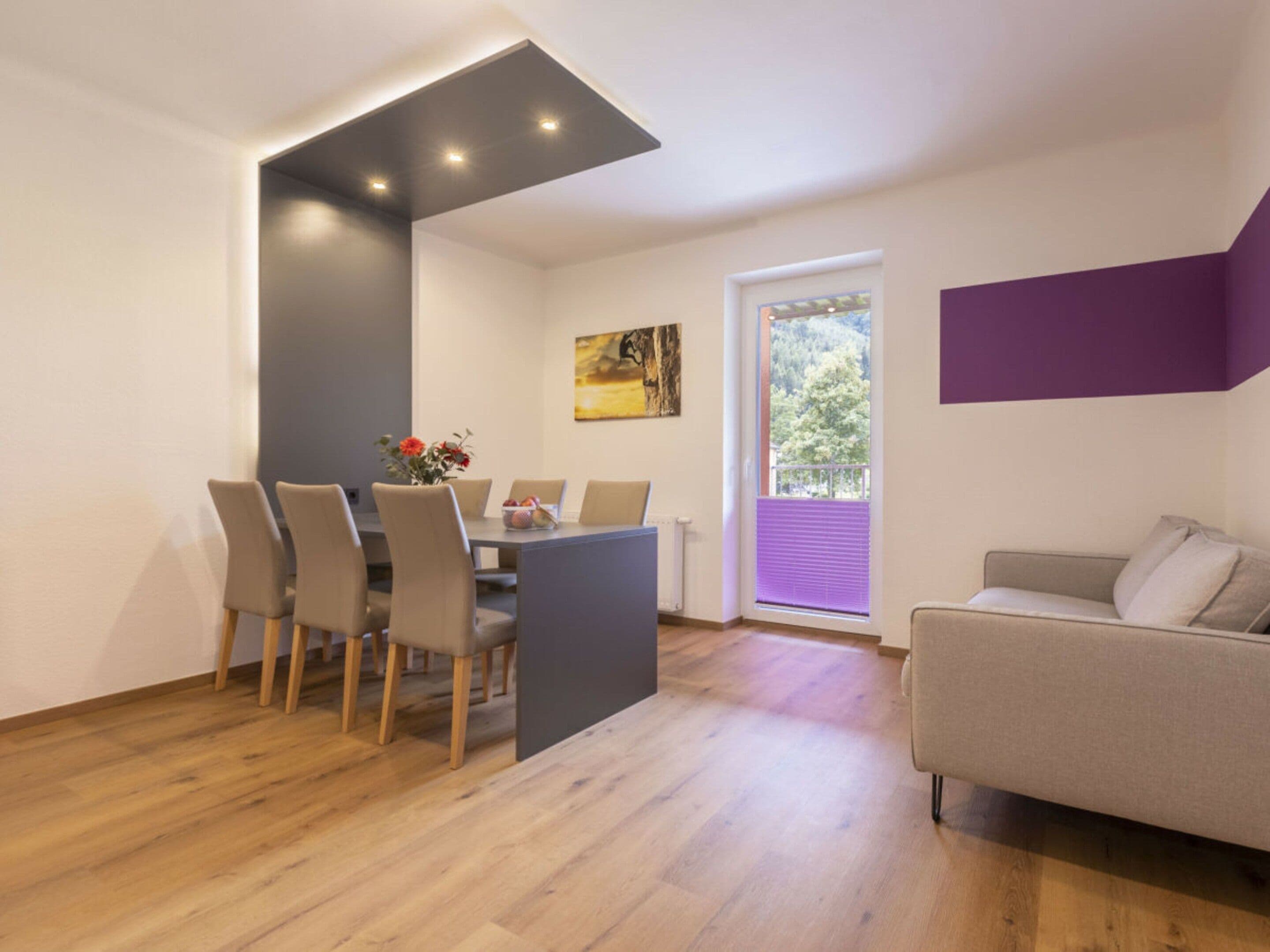 A modern living space with a dining area, a sofa, and a window with blinds.