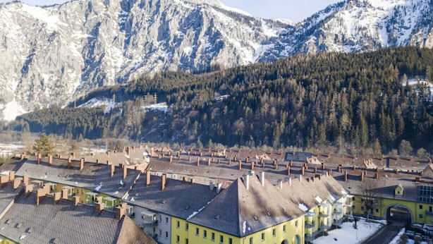 Eine Stadt mit traditioneller Architektur, einem verschneiten Berg im Hintergrund und einem klaren Himmel.