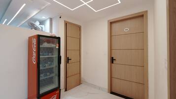 Una habitación con un refrigerador Coca-Cola, puertas de madera y un techo con lámparas geométricas.