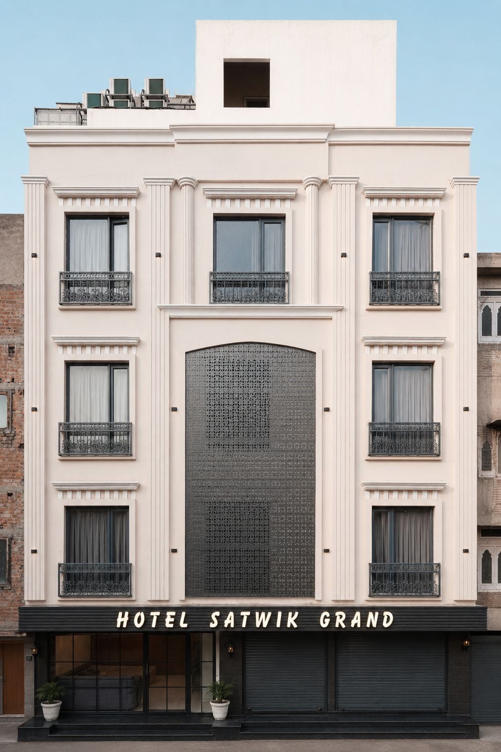 Un hotel con fachada moderna, varios balcones y una amplia entrada central.