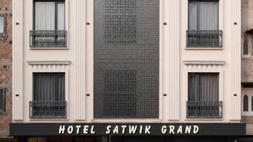 Un hotel con fachada moderna, varios balcones y una amplia entrada central.