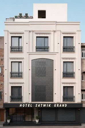 Un hotel con fachada moderna, varios balcones y una amplia entrada central.