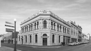 Um edifício histórico com arquitetura clássica, apresentando janelas em arco e molduras decorativas.