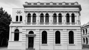 Edifício clássico com fachada simétrica, grandes janelas em arco e entrada imponente.