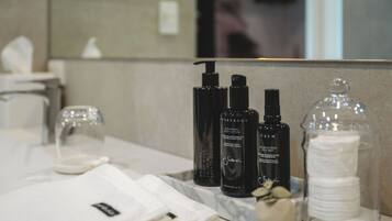 A bathroom vanity with toiletries and a glass container of cotton pads.