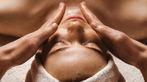 Uma pessoa recebendo tratamento facial, com as mãos no rosto, envolvida em uma toalha.