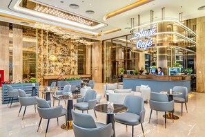 Un moderno vestíbulo de hotel con recepción, zona de estar e iluminación decorativa.