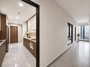 Un interior moderno con zona de cocina, un pasillo y un ventanal con vistas a edificios.