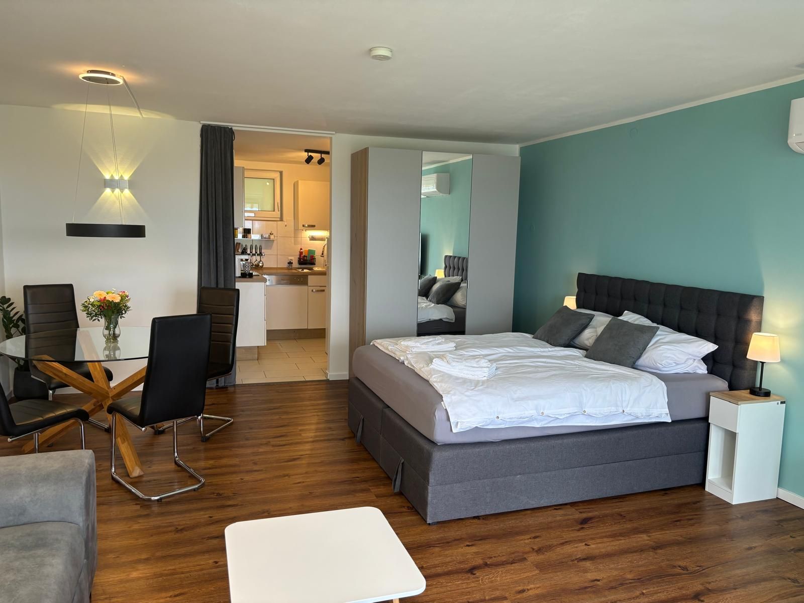 Ein modernes Hotelzimmer mit einem großen Bett, einer Essecke und einer Küchenzeile.