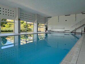 An indoor swimming pool with clear windows, a tiled floor, and a staircase leading to an upper level. - Modern vacation apartment with panoramic views and a cozy, comfortable atmosphere (Oberteuringen)