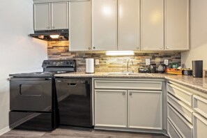 A kitchen with a stove, dishwasher, and granite countertop. - Spacious 2BR Near NASA + Pool (Houston)