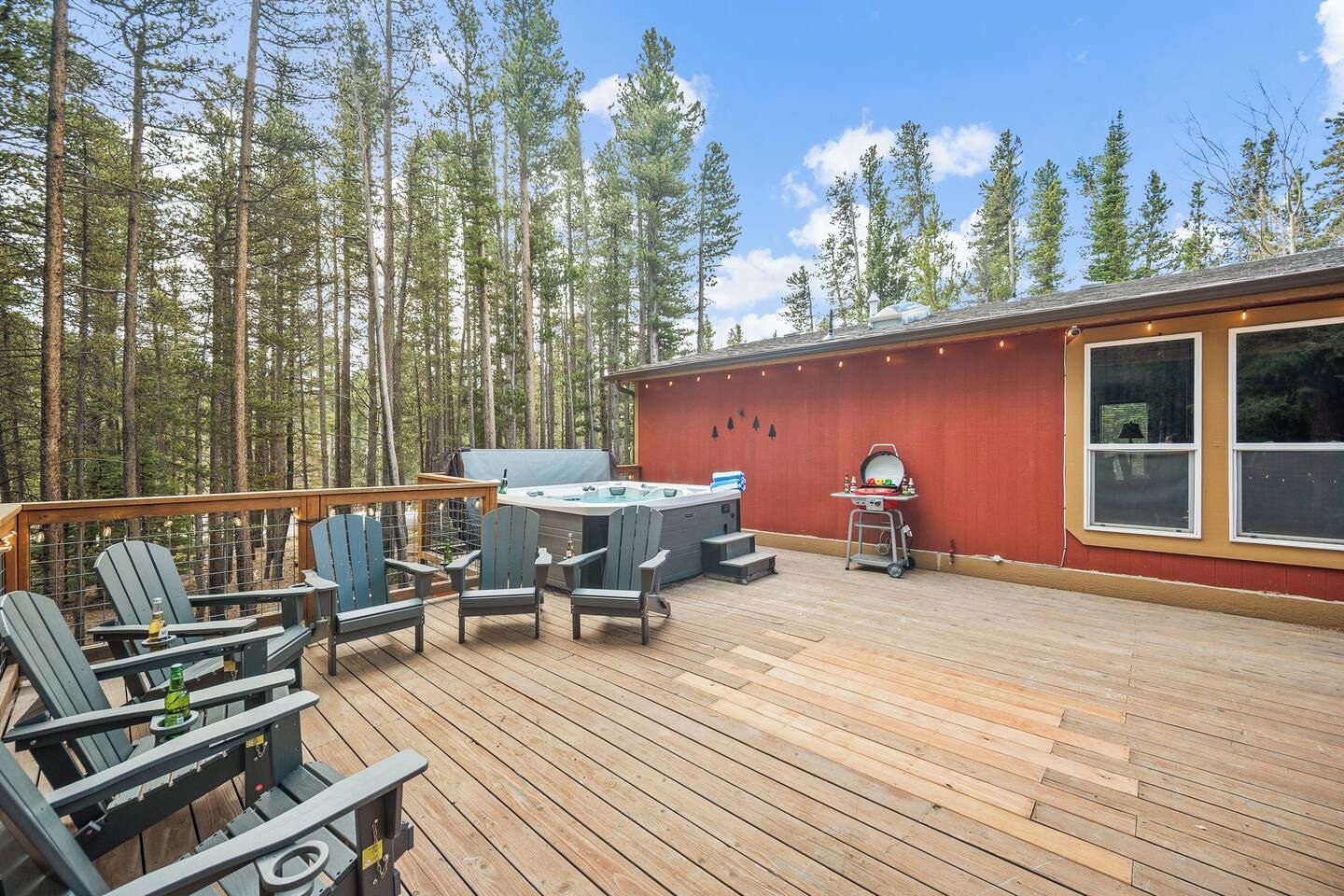 A deck with Adirondack chairs, a hot tub, and a grill area.