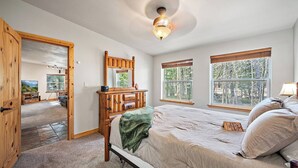 Ein Schlafzimmer mit einem Bett, einem Holzschrank, einem Spiegel und einer Deckenleuchte.