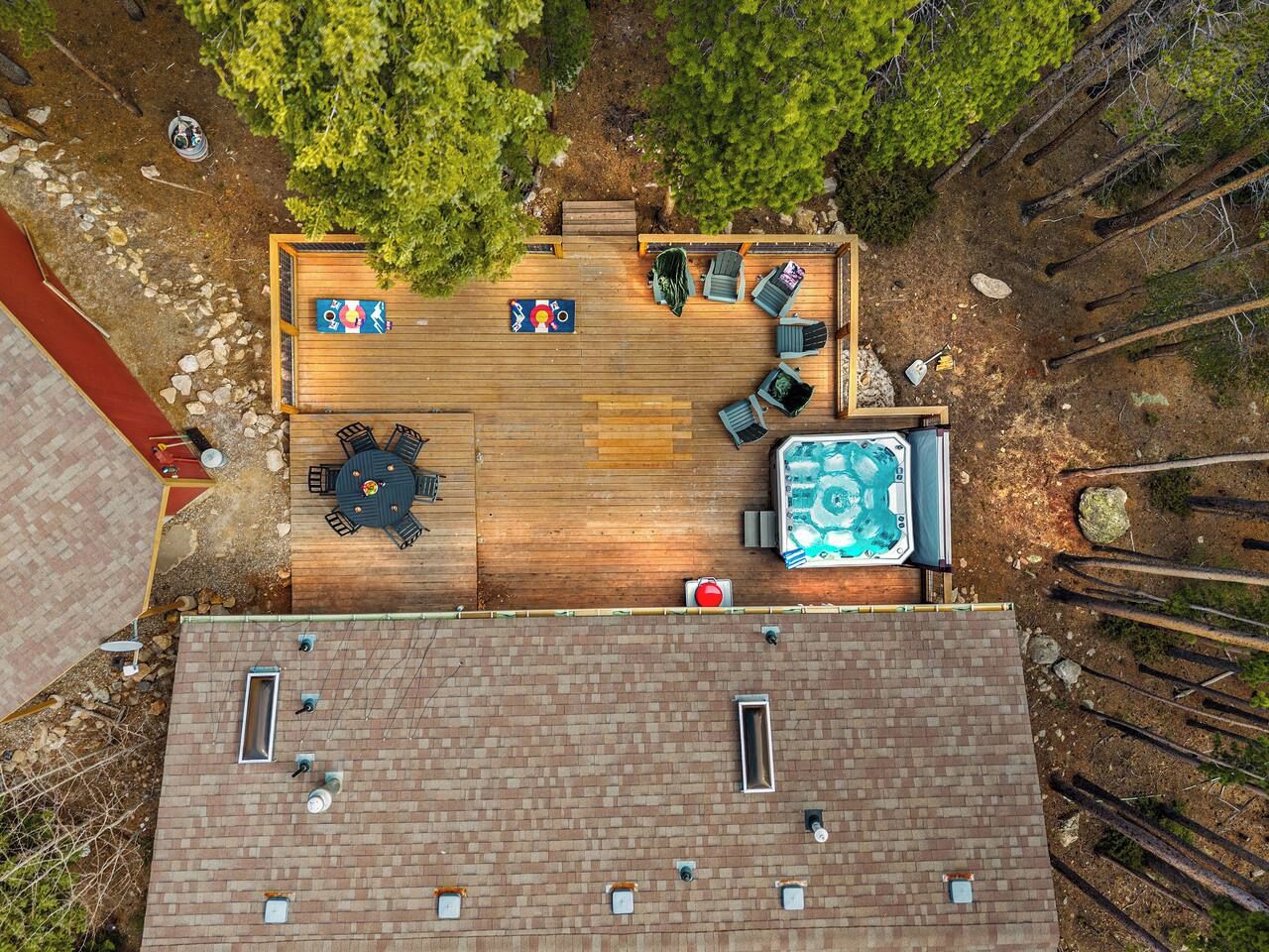 An aerial view of a rooftop deck with a hot tub, seating area, and a table.