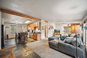 A spacious living area with a sofa, a television, and a dining table. - Hot Tub | Dog Friendly | Hike & Ski | 10K ft (Idaho Springs)