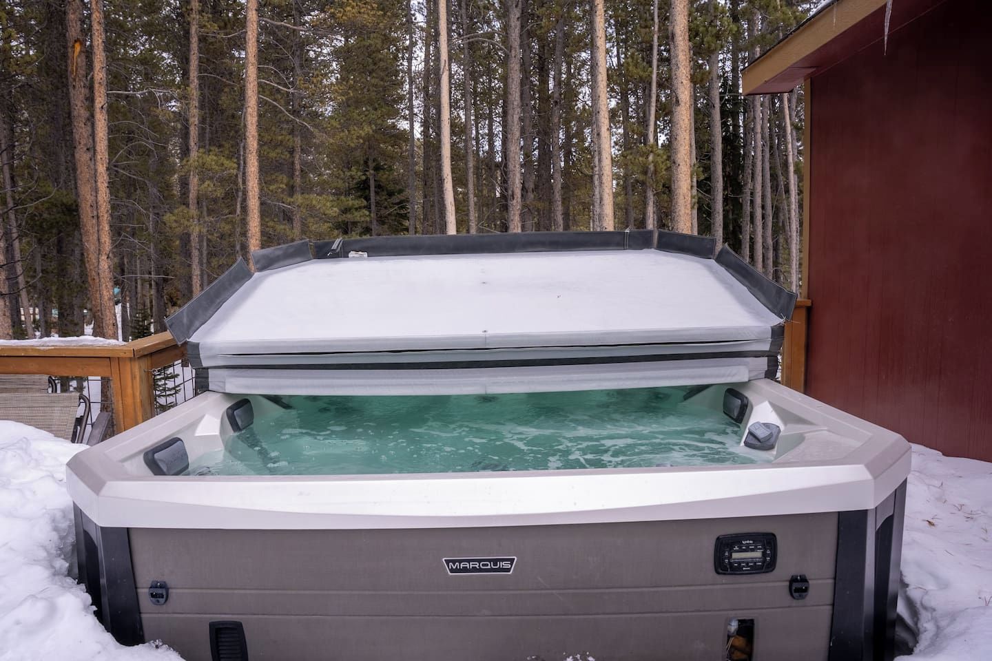A spa hot tub with a wooden deck and a red building in the background.