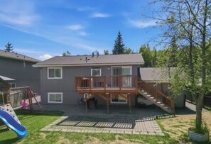 A residential property with a deck, a slide, and a staircase leading to a second floor.